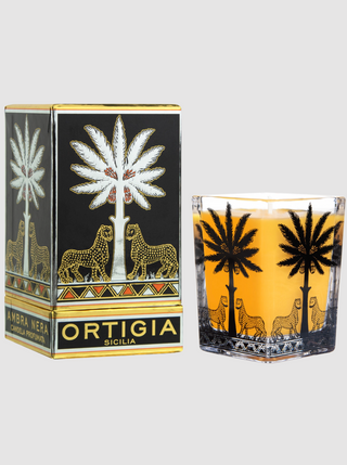 Candle with decorative design and packaging featuring palm trees and lions, branded 'Ortigia'.