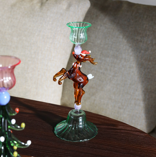 Glass reindeer with a green glass cup on its back, sitting on a wooden surface.