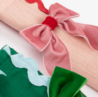 Close-up of pink and green velvet bow decorations on a white background