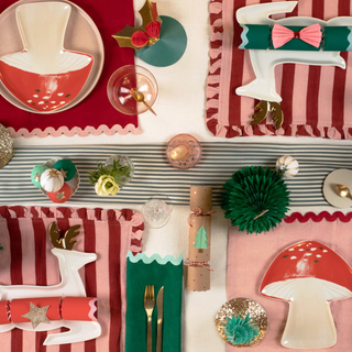 Decorative table setting with red, green, and white elements on a striped tablecloth.