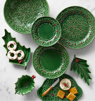 Set of green ceramic plates with holly design on a marble surface