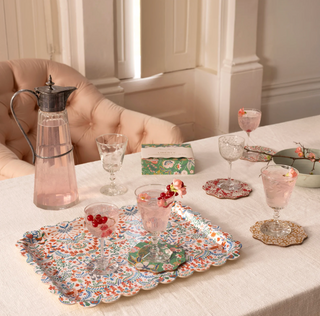 Table setting with decorative platters, glasses, and a pitcher on a light-colored surface.