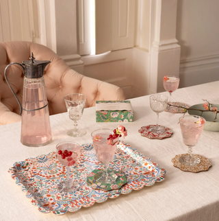 Table setting with patterned platters, glasses, and a pitcher on a light-colored surface.