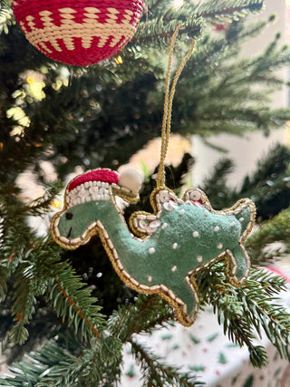 Decorative Christmas ornament of a green loch ness monster with a red hat on a tree.