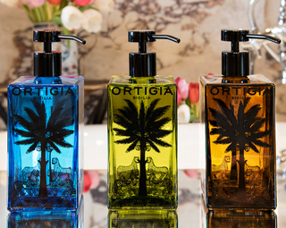 Three Ortigia Sicilia soap dispensers in blue, green, and brown with palm tree design.