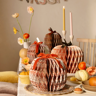 Decorative pumpkins with ribbons on a table with flowers and candles
