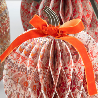 Decorative pumpkin with floral pattern and orange bow against a blurred background