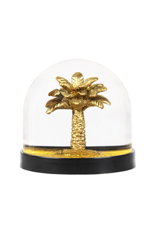 Gold palm tree figurine inside a clear glass dome with black base on a white background