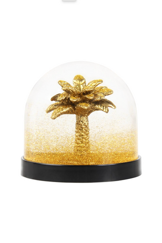Gold palm tree inside a clear dome with a black base on a white background